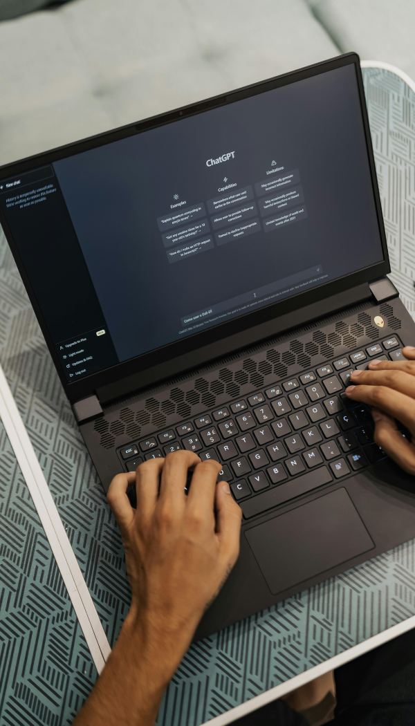Das Bild zeigt eine Person, die auf einem Laptop tippt. Auf dem Bildschirm des Laptops ist die ChatGPT-Oberfläche zu sehen.